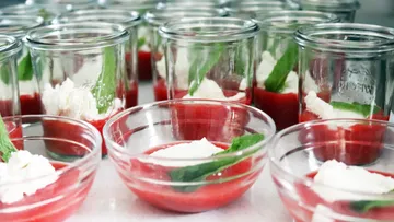 Dessert glasses with red puree and cream, decorated with mint.