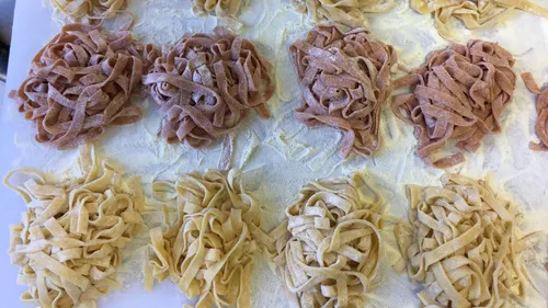 Hausgemachte Pasta-Nester liegen auf einem bemehlten Tisch.