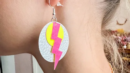 Ohrringe hängen an Ohrläppchen, mit buntem Blitzdesign.