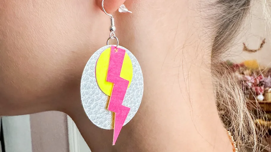 Ohrringe hängen an Ohrläppchen, mit buntem Blitzdesign.