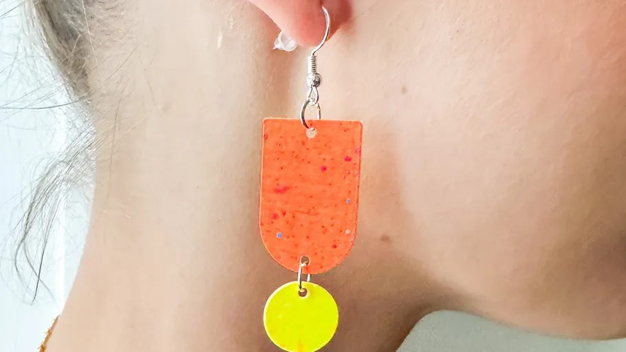 Bright coloured earrings hanging on one ear