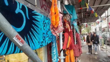 Bright cloths hang from scaffolding in a street.