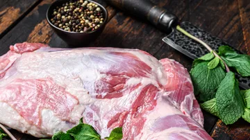 Raw meat lies next to spices on a wooden background.