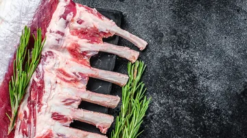 Ribs lie on a bulletin board surrounded by rosemary.
