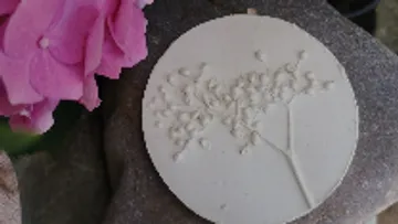 White stone with floral relief, situated next to a flower.