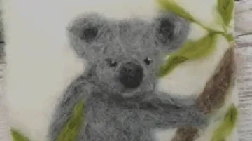 Koala climbs on a branch with green leaves.