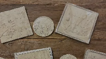 Sechs geprägte Platten liegen auf einem Holztisch.