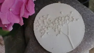 Kreisförmige Platte mit Pflanzenmotiven, neben einer Blume.