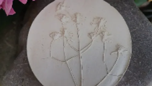 Circular plaque with embossed plant motifs.