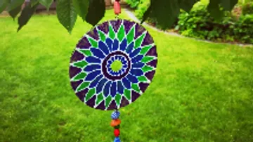 Colorful mandala wind chime hanging outdoors.