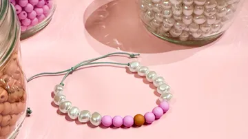 Beaded bracelet on pink surface near bead jars.