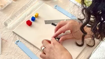 Person works on surface with colorful blocks and tools.