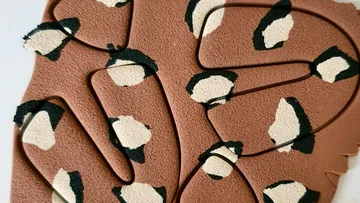 Colourful, wavy wire shapes lie on a piece of leather.