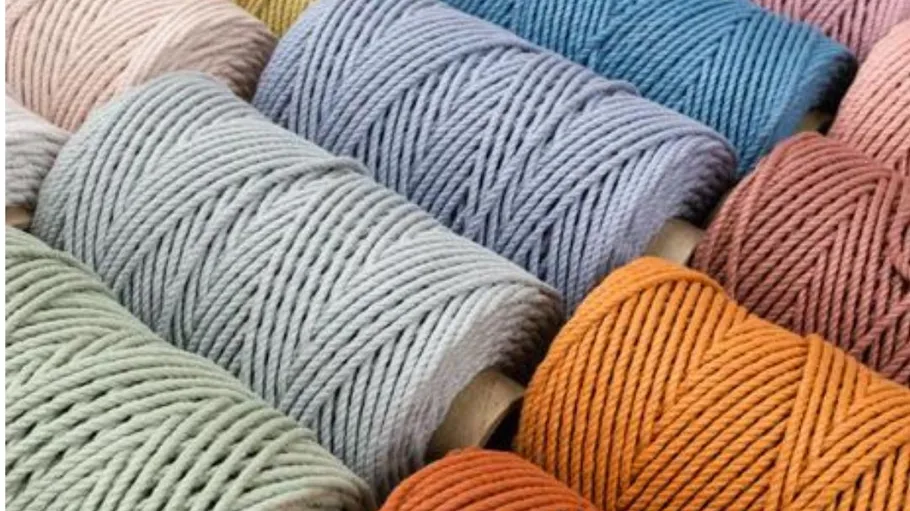 Colourful spools of thread lie neatly side by side on wood.