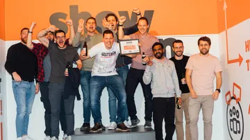 Group of men celebrate together with certificate and beer.