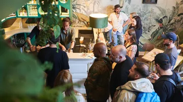 Menschen stehen um eine Bar, während Getränke zubereitet werden.