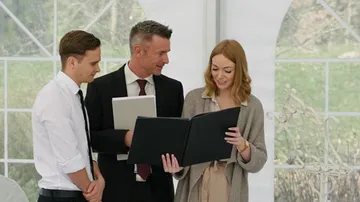 Drei Personen betrachten ein Dokument in einem Zelt.