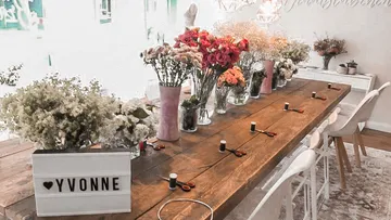 Ein Tisch mit Blumenarrangements und Bastelmaterialien.