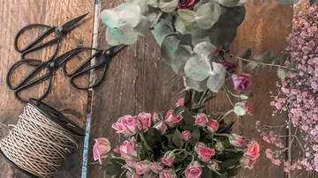 Blumen und Werkzeuge auf einem Holztisch arrangiert.