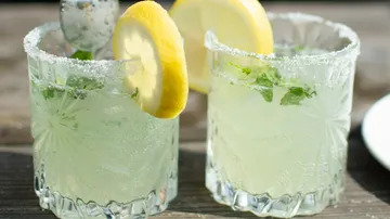 Two glasses of lemonade green cocktail and lemon slices.