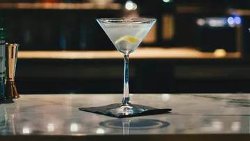 Martini glass sits on a counter with a slice of lemon.