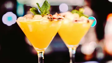 Zwei Cocktails stehen auf einem Tisch, umgeben von Licht.