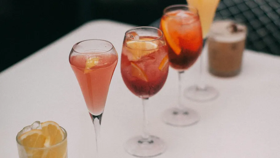 Colourful cocktails sit on a table with citrus fruits.