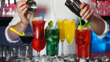 Bunte Cocktails werden auf einer Bar vorbereitet und serviert.