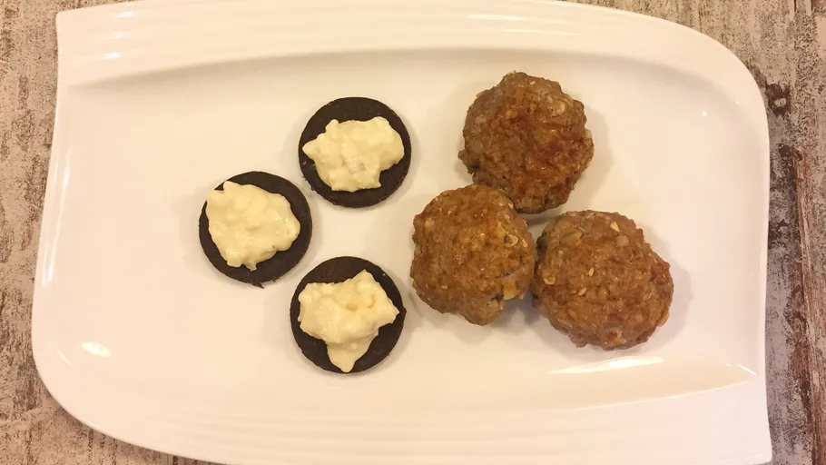 Three meatballs and four small black cookies with dip.