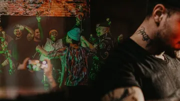 Groups of people party vividly under colorful lights.