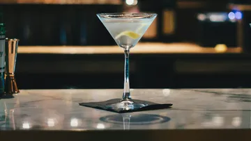 Ein Martini-Glas steht auf einem Marmorbartresen.