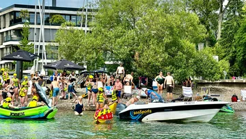 People swim and relax on the beach of a body of water.
