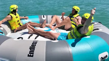 People sit happily on an inflatable platform in the water.