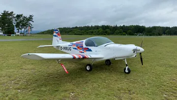 Ein kleines, buntes Flugzeug steht auf einer Wiese.