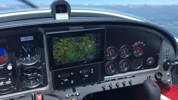 Aircraft cockpit with instruments shows map and information.