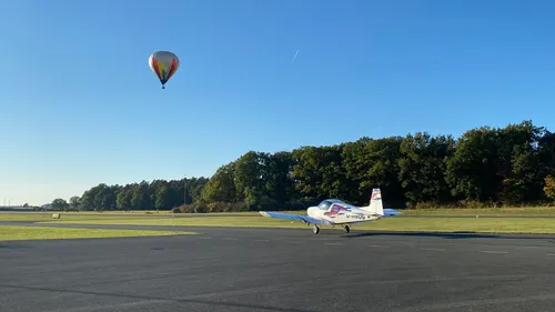 An airplane rolls while a hot air balloon floats.