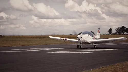 An airplane rolls on a runway in open countryside.