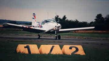 An airplane rolls on a runway in nature.