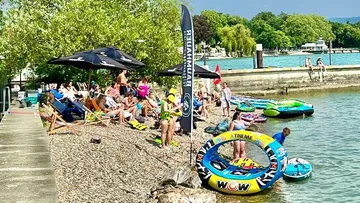 Beach with sunbathing, swimming tires in the water, sunny.