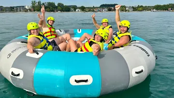 Five people on a large inflatable boat in the water.