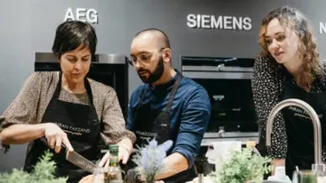 Three people cook together in a modern kitchen.