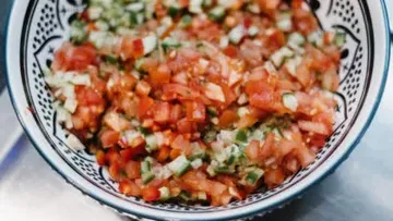Schüssel mit gewürfeltem Gemüse und Kräutern, frisch zubereitet.