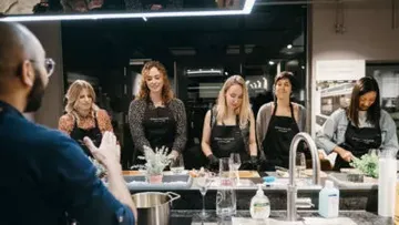 Eine Gruppe von Frauen lernt beim Kochen in einer modernen Küche.