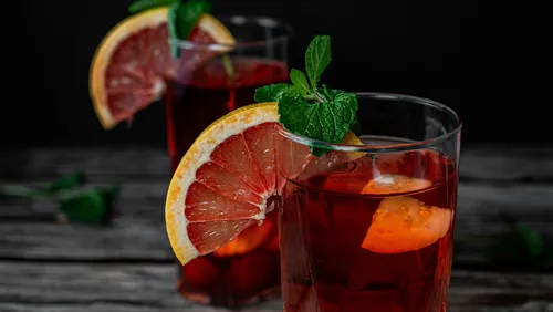Zwei Gläser mit rotem Getränk, garniert mit Zitrone und Minze.