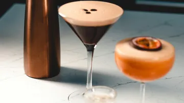 Cocktails stehen auf einem Tisch, umgeben von modernen Gläsern.