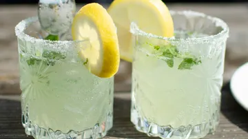 Zwei Gläser mit einer limonadigen Mischung und Zitronenscheiben.