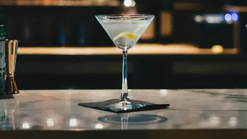 Ein Cocktailglas steht auf einem Tisch mit Unterlage.