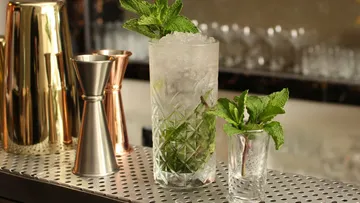 Glas mit Eis und Minze steht auf einer Bartheke.