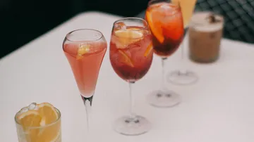 Bunte Cocktails stehen auf einem Tisch, entspanntes Ambiente.
