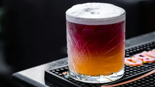 Colorful cocktail with foam on a bar counter.